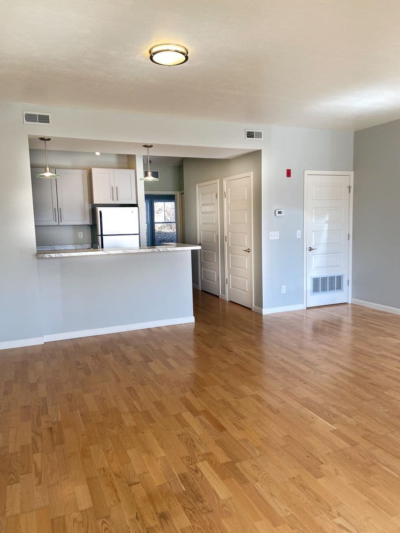 Sunlit living area opening to the kitchen with pendant lighting