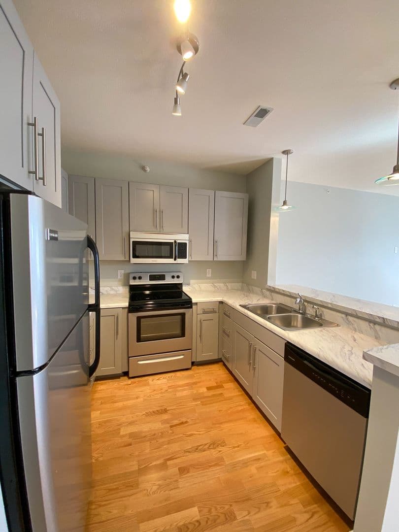 Galley kitchen with stainless appliances and warm hardwood floors