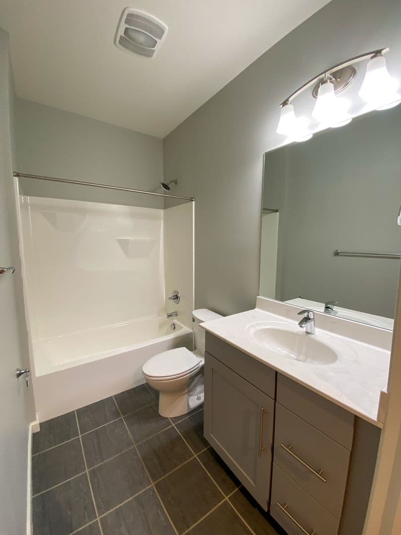 Bathroom with soaking tub, vanity storage, and designer tile floors