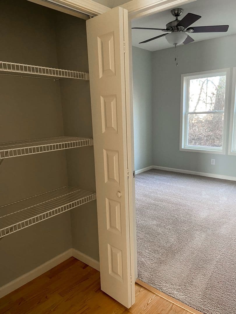Bedroom with ceiling fan and oversized closet with built-in shelving