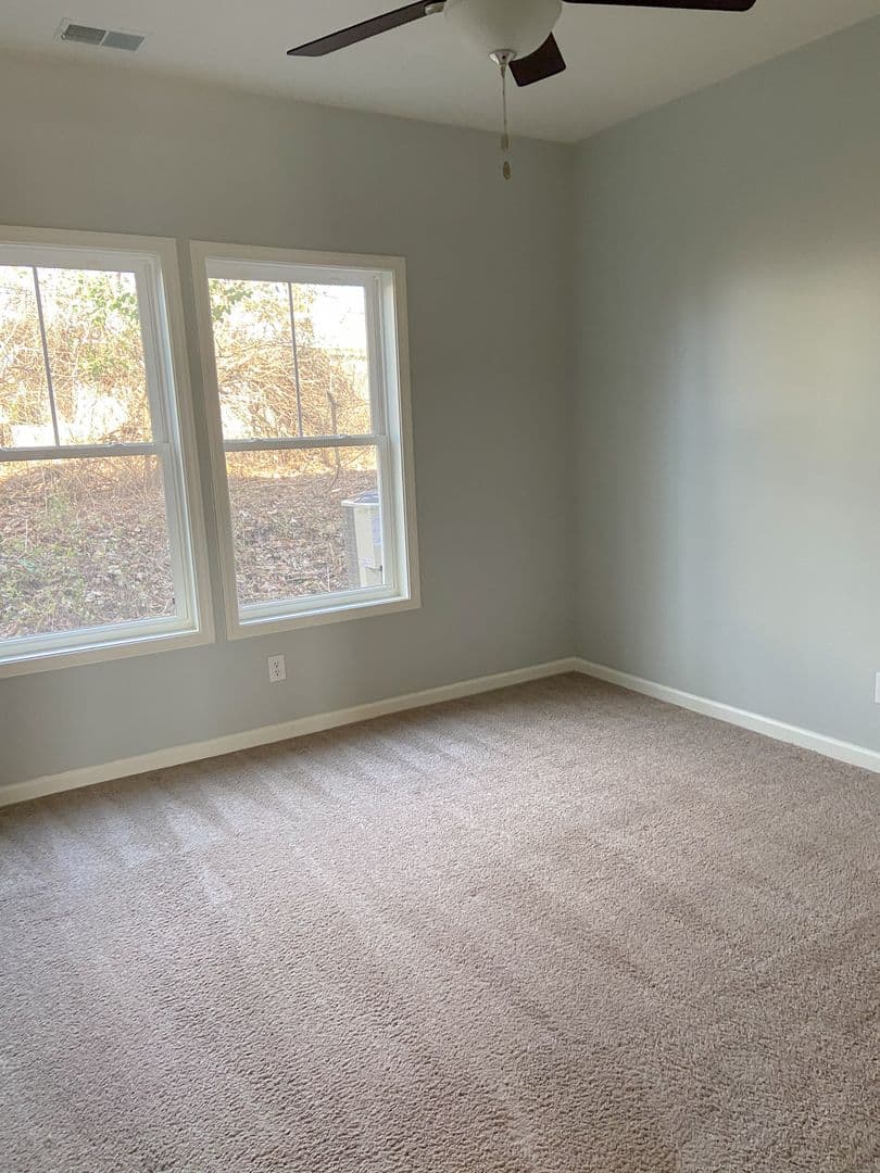 Bright bedroom with double windows and plush carpet
